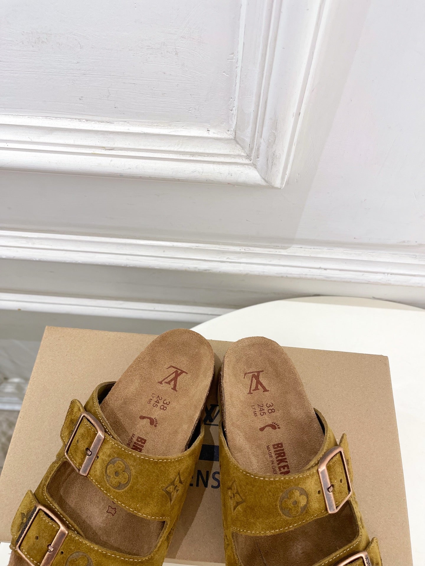 Close view of tan monogram slide sandals with two adjustable buckles