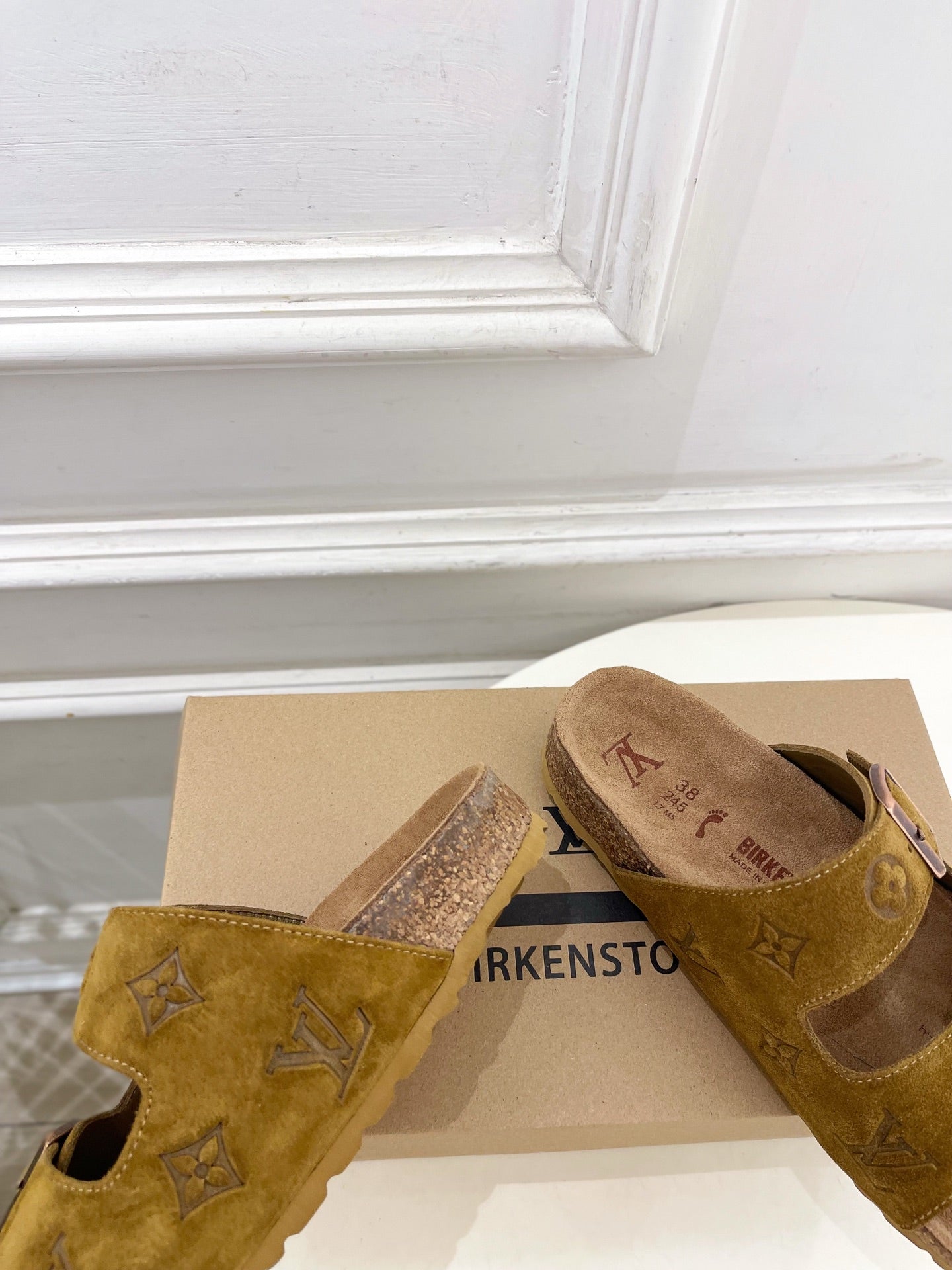 Tan suede-style slide sandals with two buckled straps, one pair in glitter finish