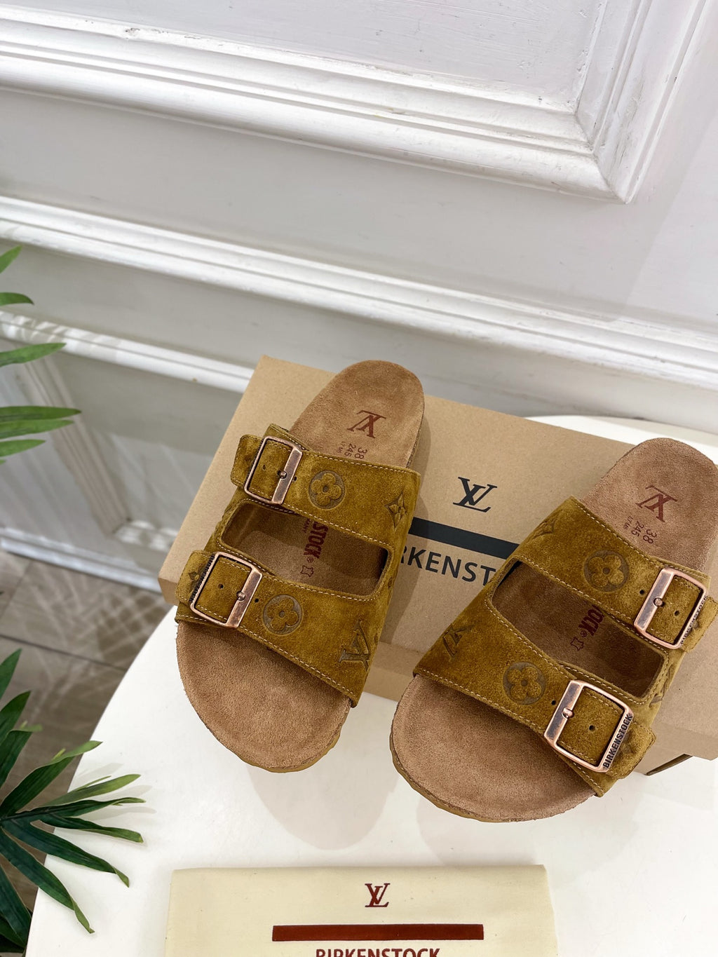 Tan monogram slide sandals with two buckled straps and cushioned soles