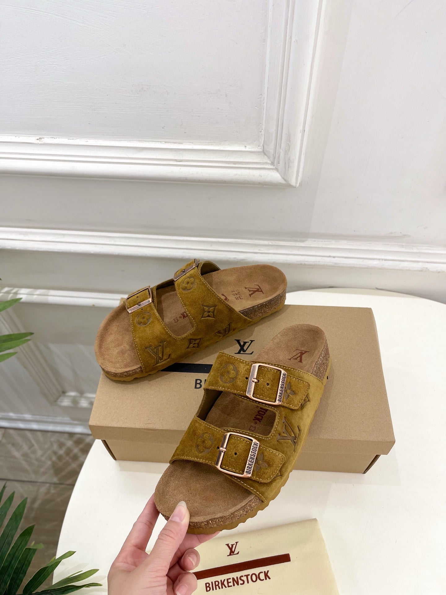 Tan monogram slide sandals with two buckled crossover straps and contoured footbed