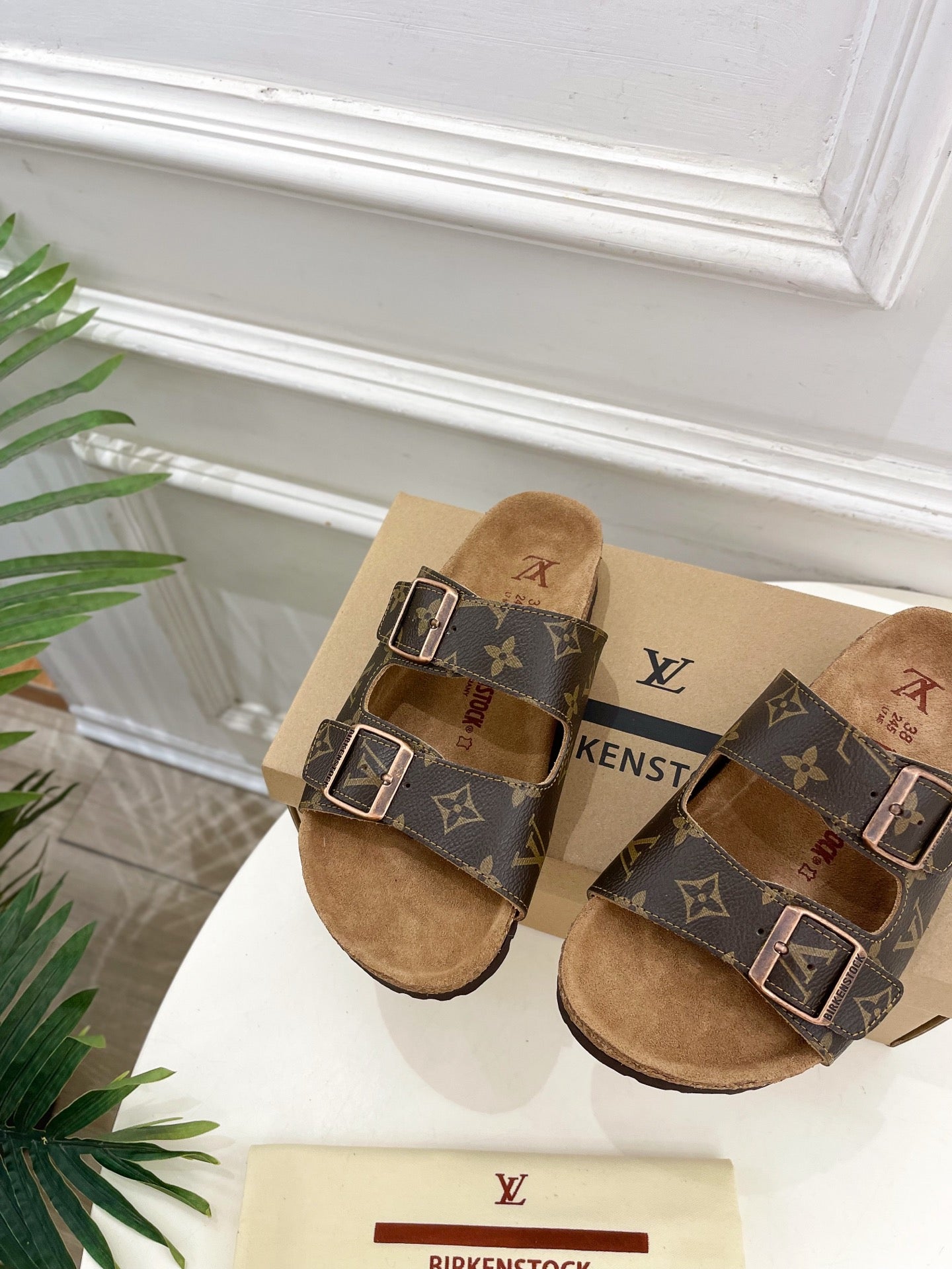Brown monogram slide sandals with twin buckles and tan suede footbed