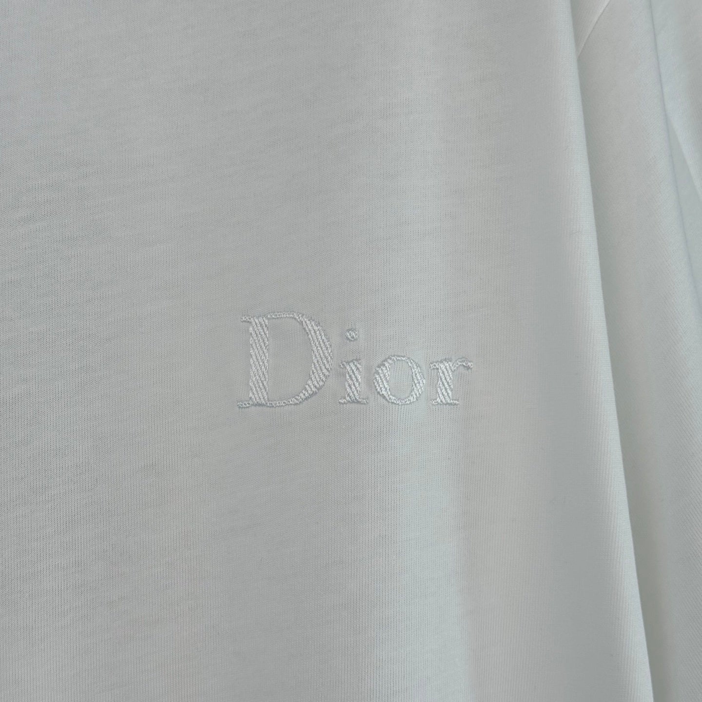White Dior T-shirt with embossed 'Dior' logo on chest.