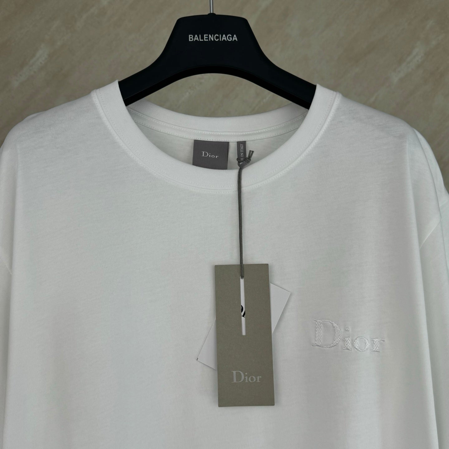 White Dior T-shirt with crew neck and hanging Dior tags, chest logo.