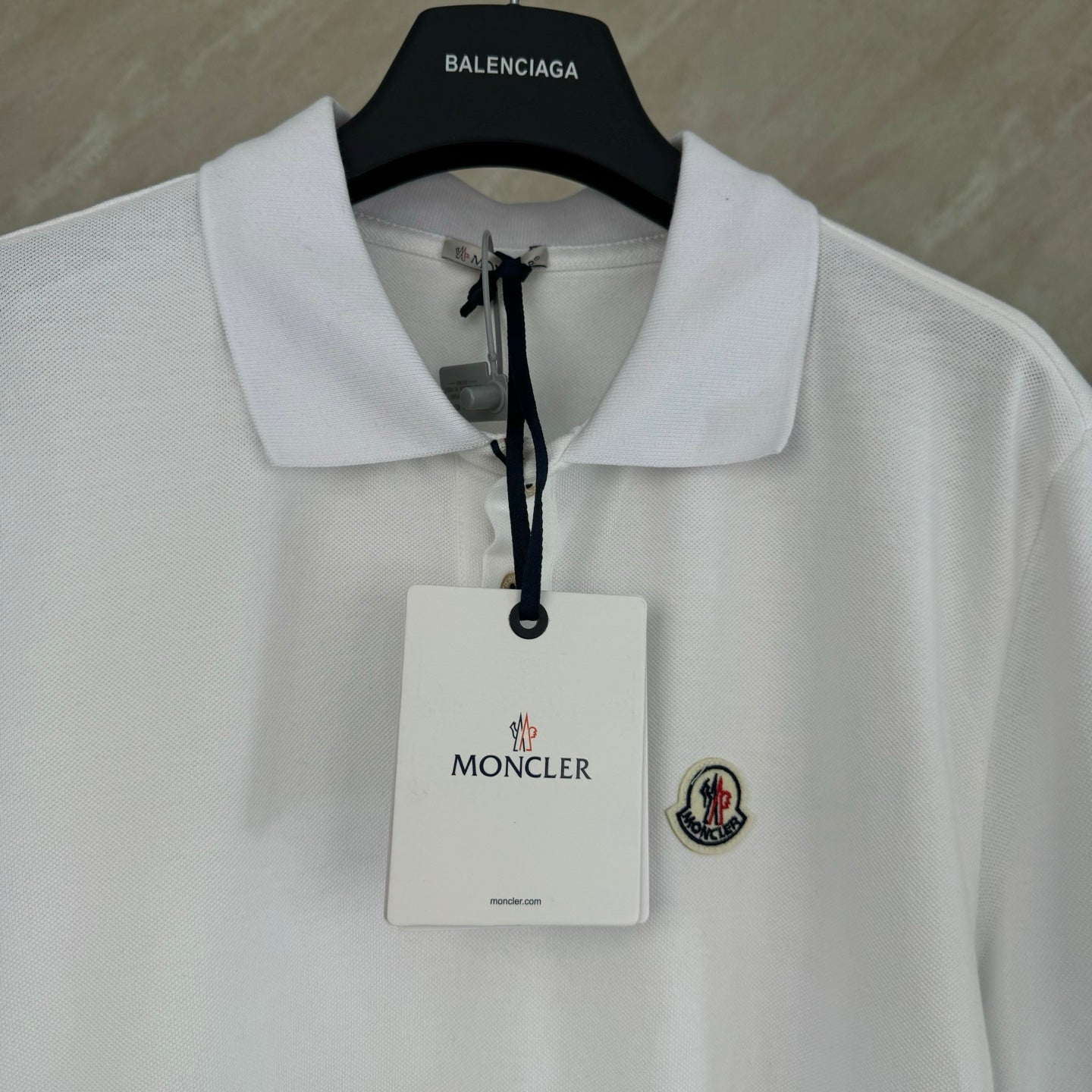 White polo shirt with neck label, hang tag, and chest crest