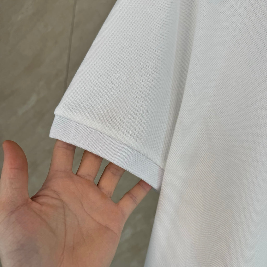 White polo shirt sleeve cuff with textured knit and stitched hem