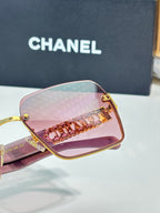 Square sunglasses close-up with pink gradient lenses and gold chain-style detail