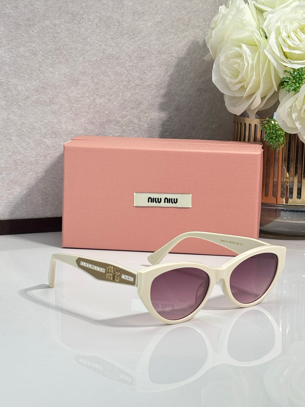 MiuMiu sunglasses with cream frames and purple tinted rounded cat-eye lenses
