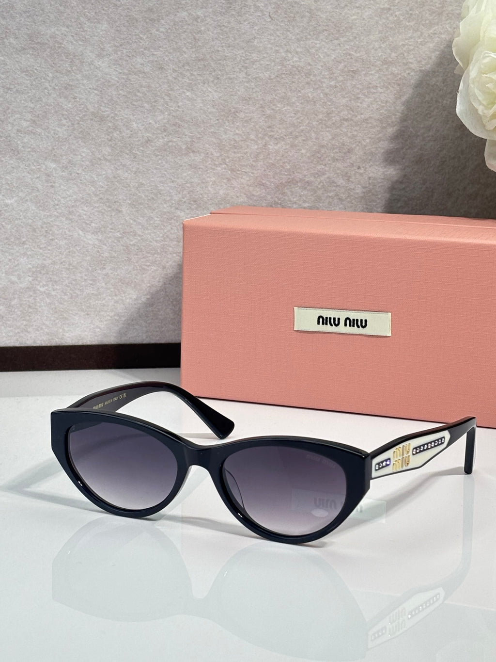 MiuMiu sunglasses with black frames and purple tinted lenses