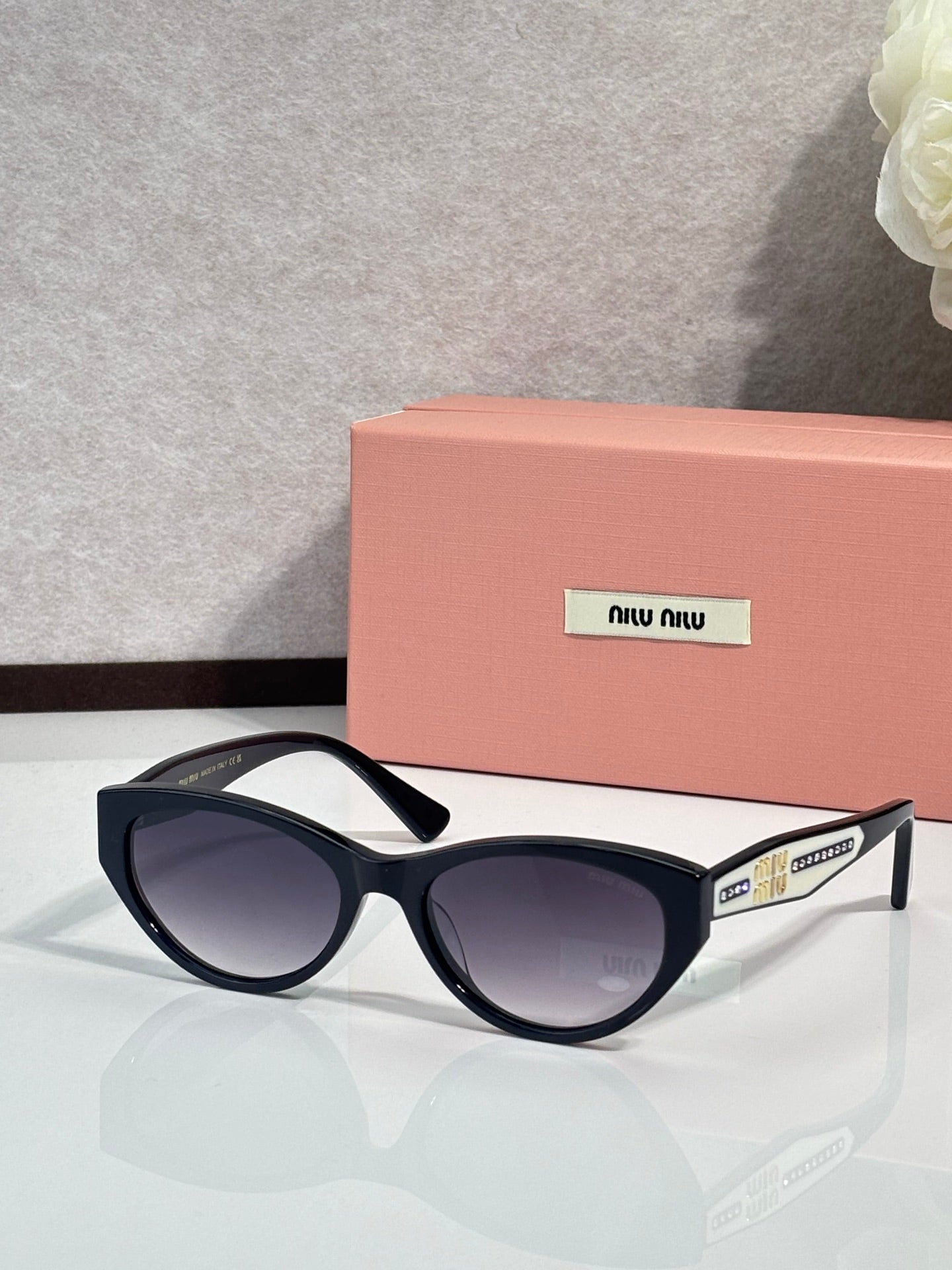 MiuMiu sunglasses with black frames and purple tinted lenses