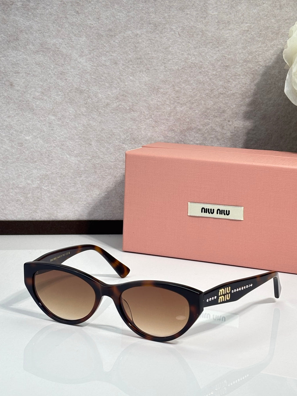 MiuMiu sunglasses with dark frames, patterned temples, and brown tinted lenses