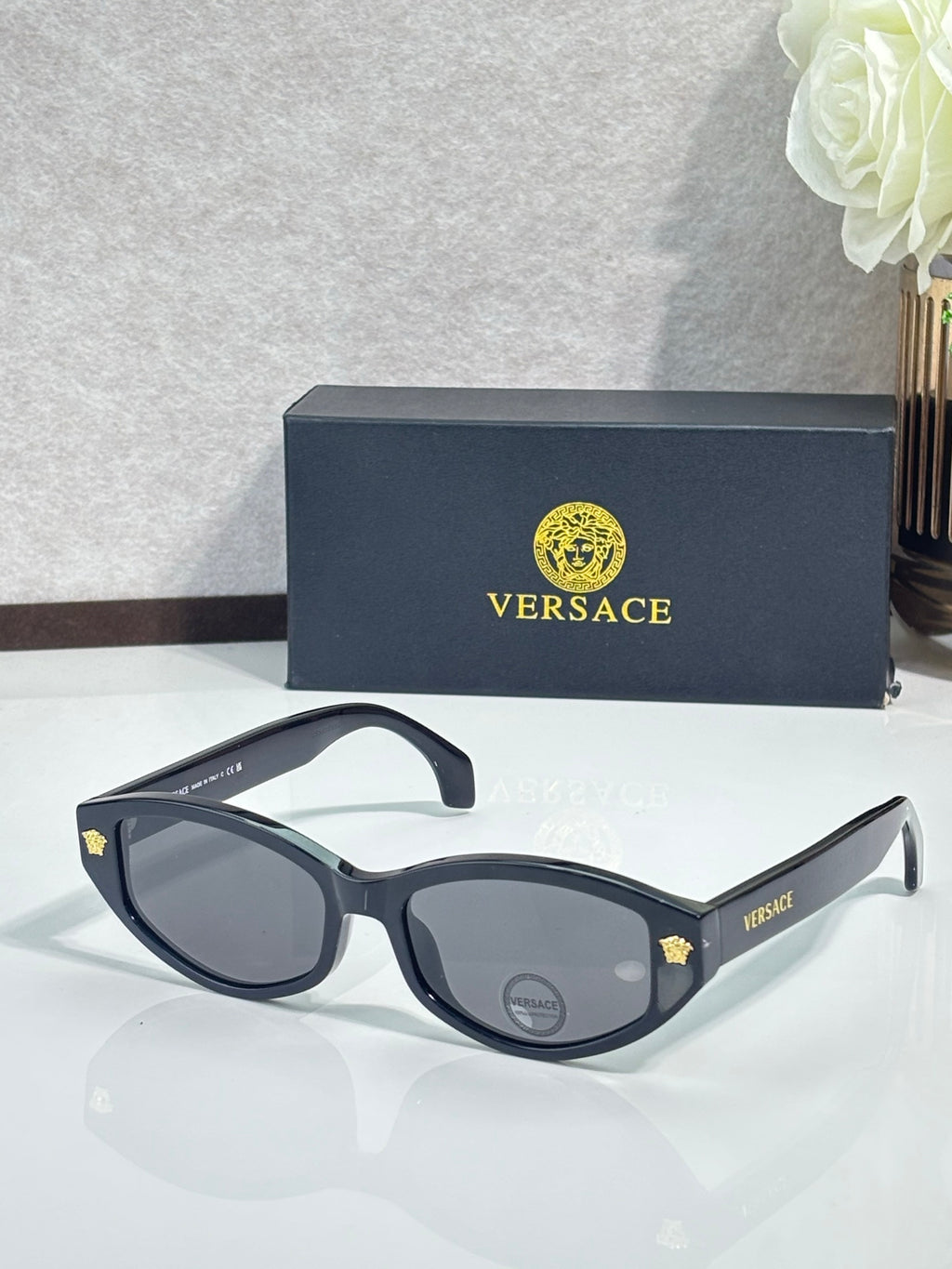 Versace sunglasses with black frame and dark lenses, gold logo detail