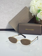 Gold-tone oval sunglasses with brown lenses and blue temple tips