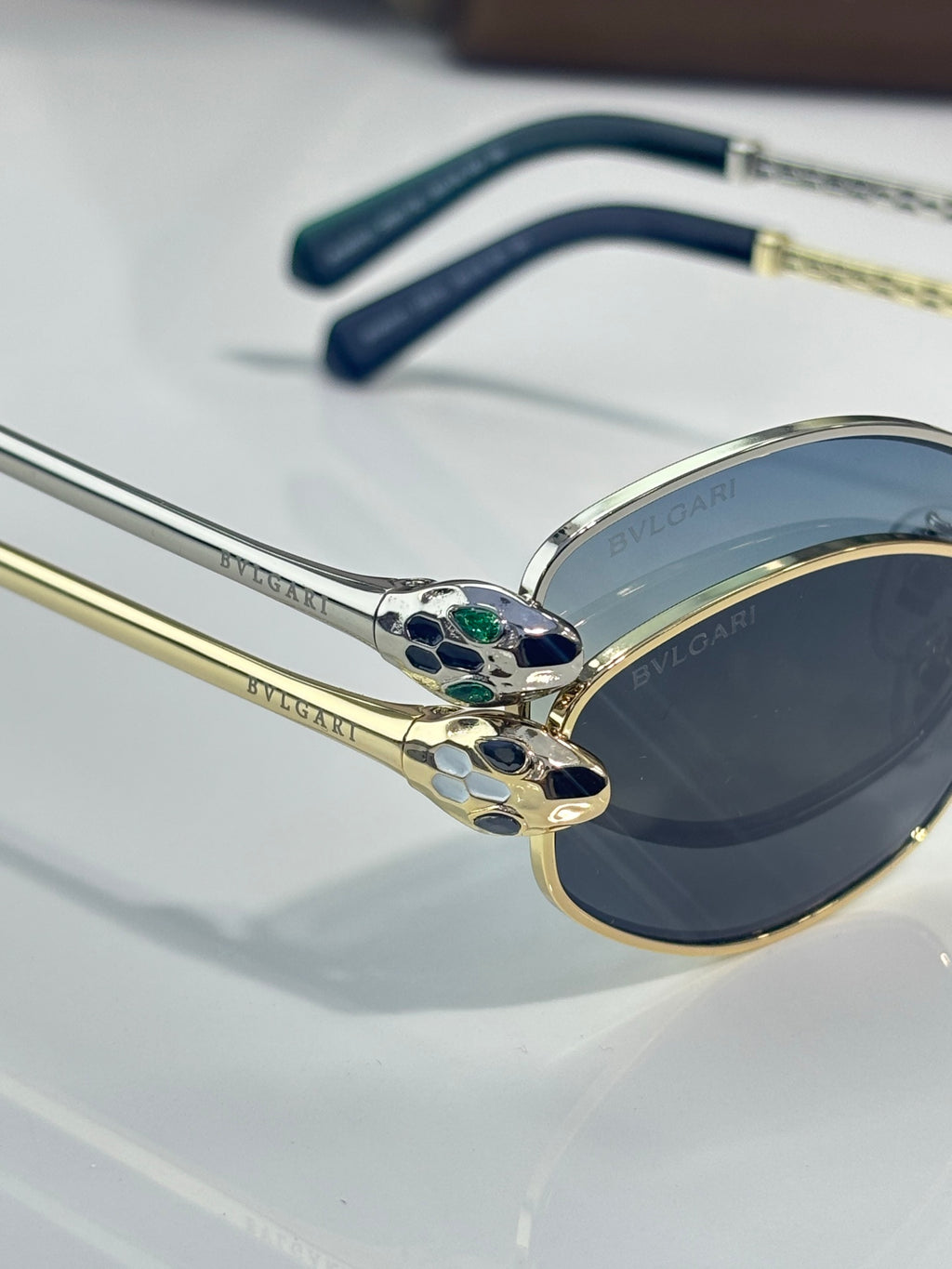 Gold and dark blue sunglasses frame with ornate crest detail on the bridge
