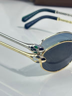 Gold and dark blue sunglasses frame with ornate crest detail on the bridge
