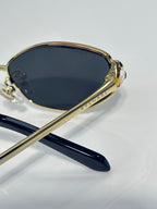 Oval sunglasses with dark lenses, gold-tone rims, and dark blue temple tips
