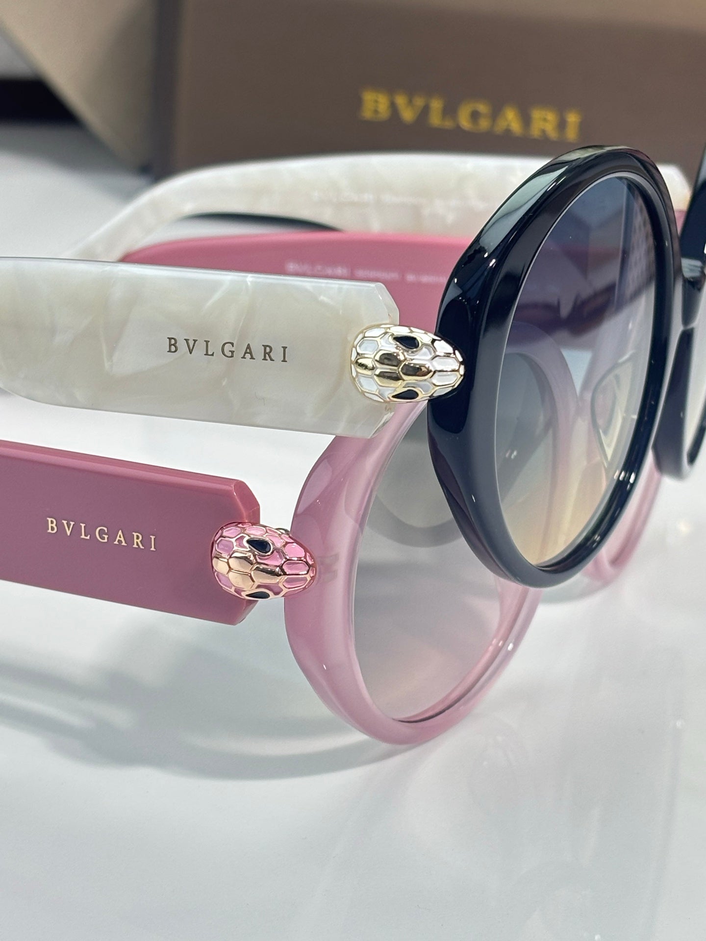 Round sunglasses with glossy pink and black frames and decorative side charms