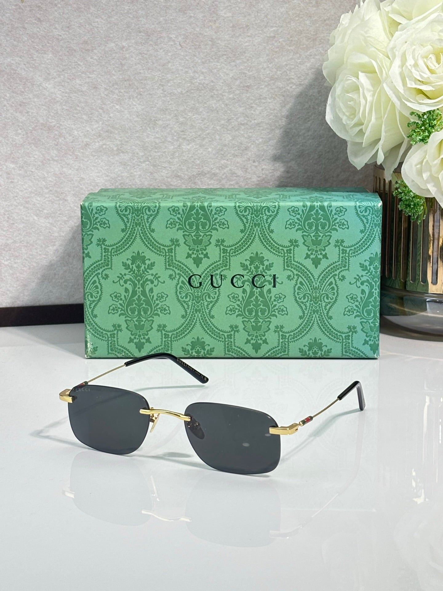 Gold rectangular sunglasses, dark gray lenses, thin black arms, front view