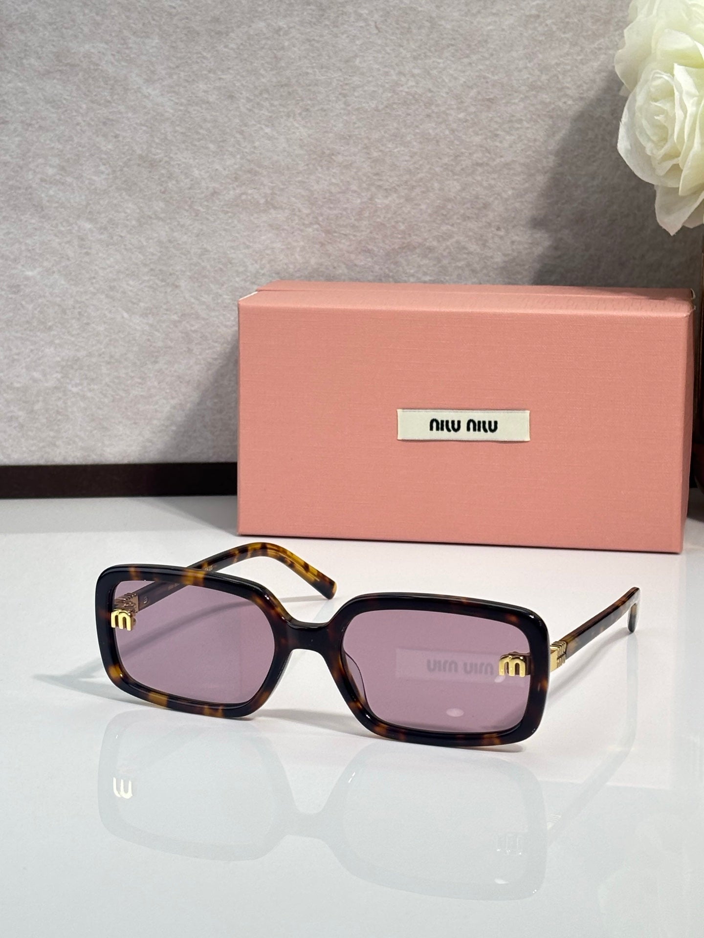 MiuMiu tortoiseshell sunglasses with purple lenses and white notch temples
