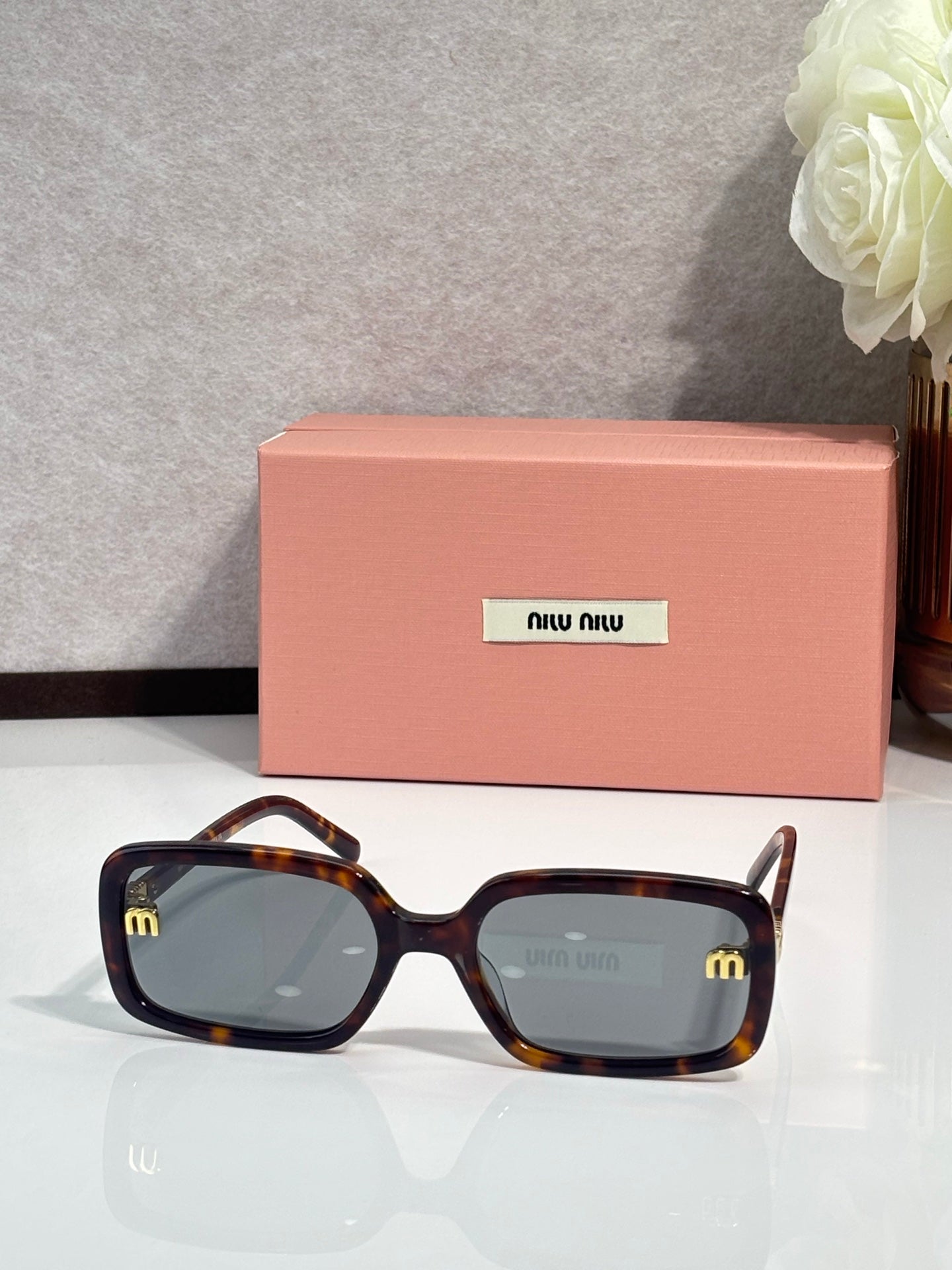 MiuMiu tortoiseshell sunglasses with blue-gray tinted lenses and gold temple logo