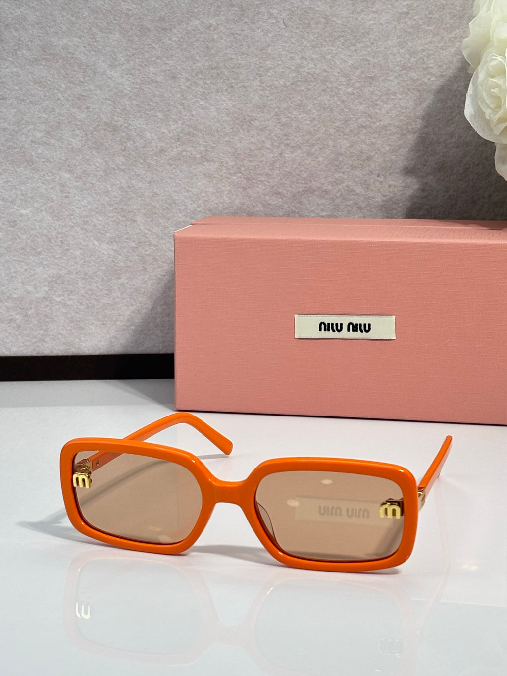 MiuMiu orange sunglasses with tinted lenses and gold logo detail on temple