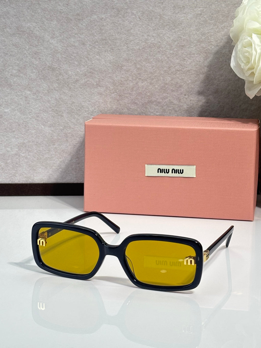 MiuMiu navy sunglasses with yellow-tinted lenses and gold logo on temple