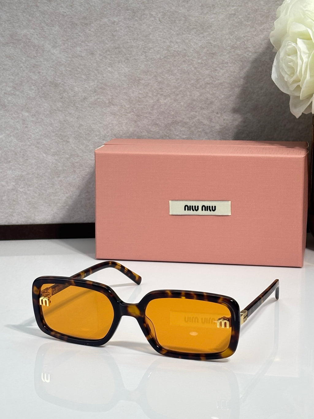 MiuMiu amber sunglasses with tortoiseshell accents and gold logo on temple