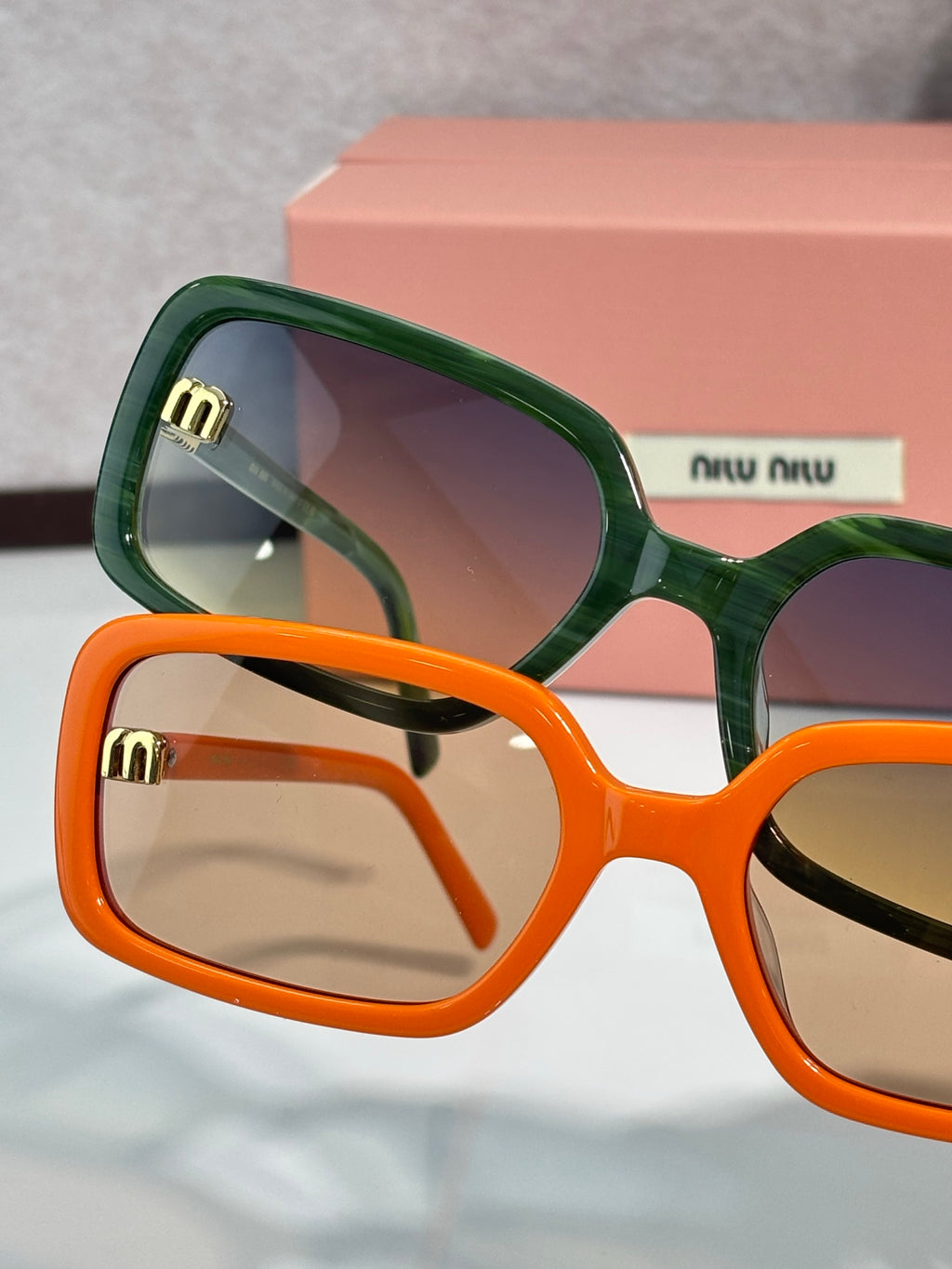 MiuMiu green and orange sunglasses, close-up of frames with gold logo