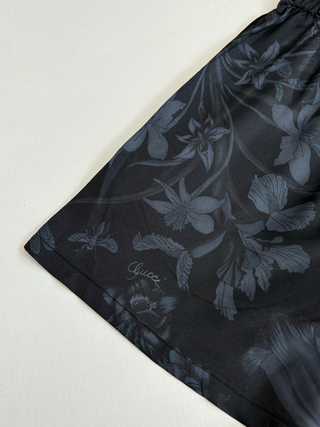 Gucci floral print shorts, dark fabric with flower motif, flat lay