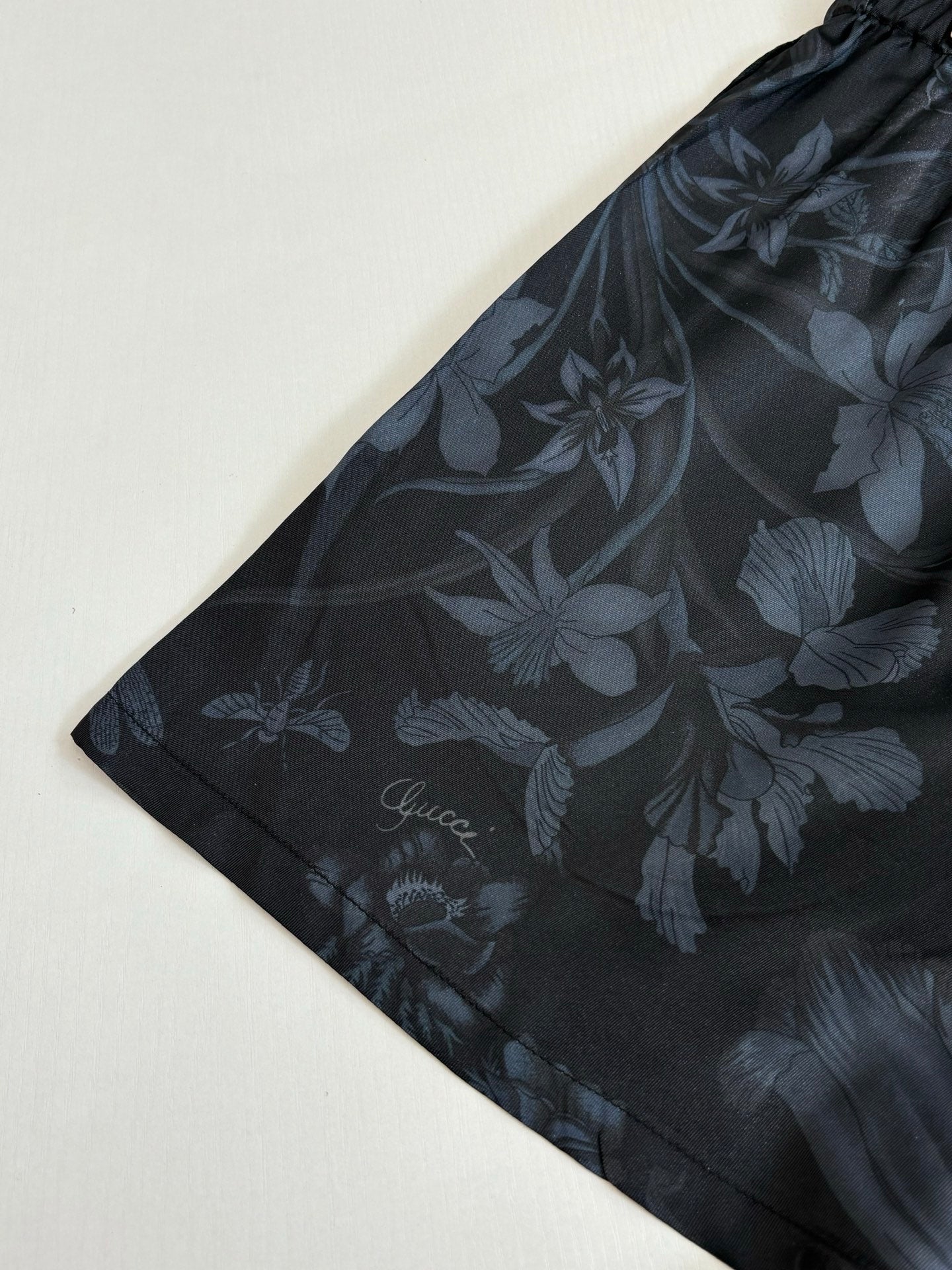 Gucci floral print shorts, dark fabric with flower motif, flat lay