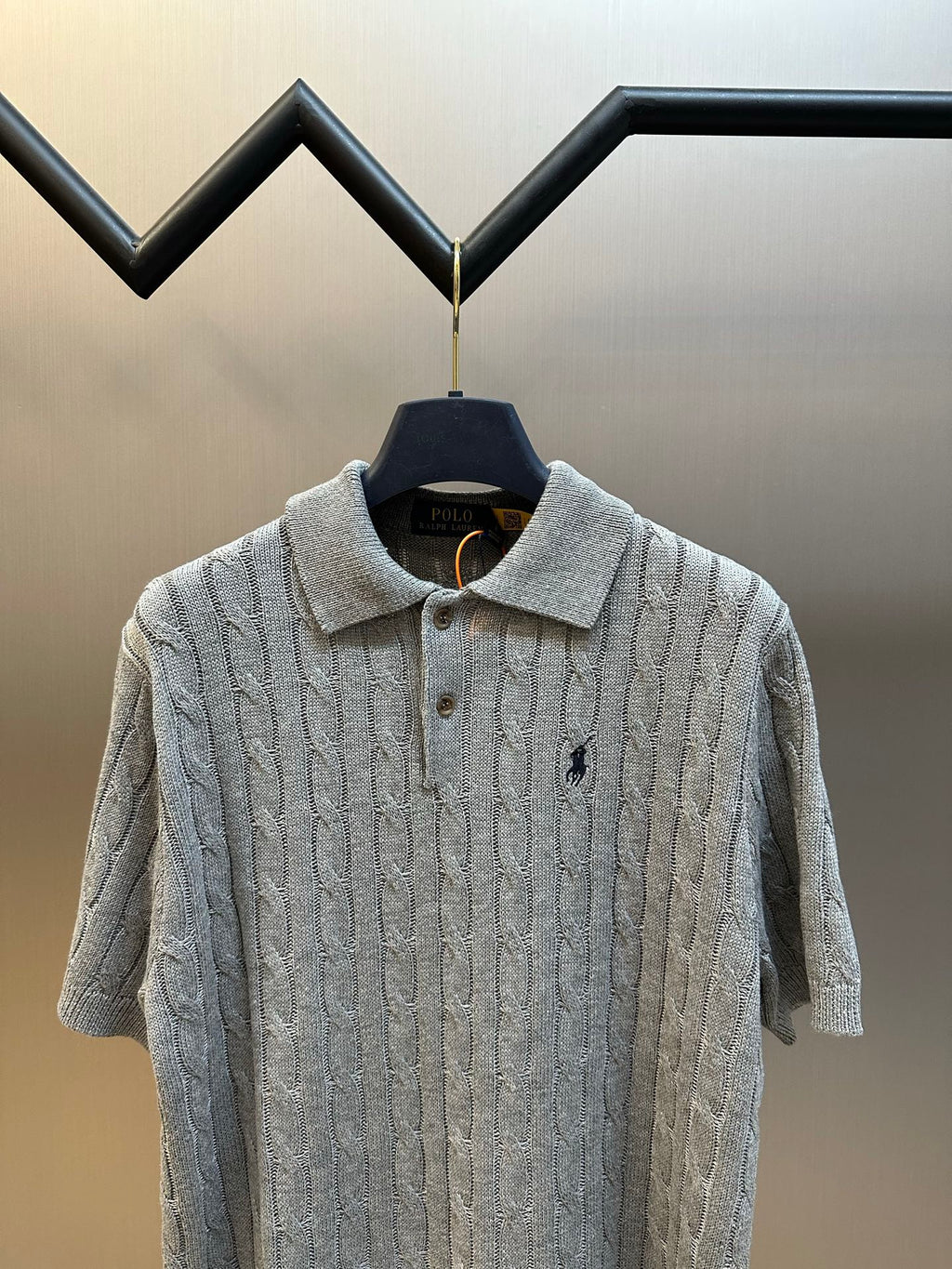 Light gray cable-knit polo shirt on hanger, collared neck with button placket