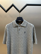 Light gray cable-knit polo shirt on hanger, collared neck with button placket