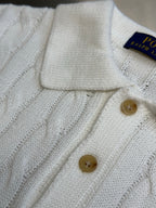 White knit polo shirt front with ribbed collar and tan button placket.