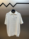 White knit polo shirt with cable texture, button placket, and small navy logo.