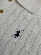 White knit polo shirt chest logo detail with cable pattern and button collar.