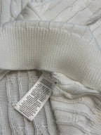 White knit polo shirt with folded fabric and attached care label tag.