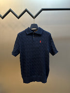 Navy cable-knit polo shirt with short sleeves, button placket, and red logo