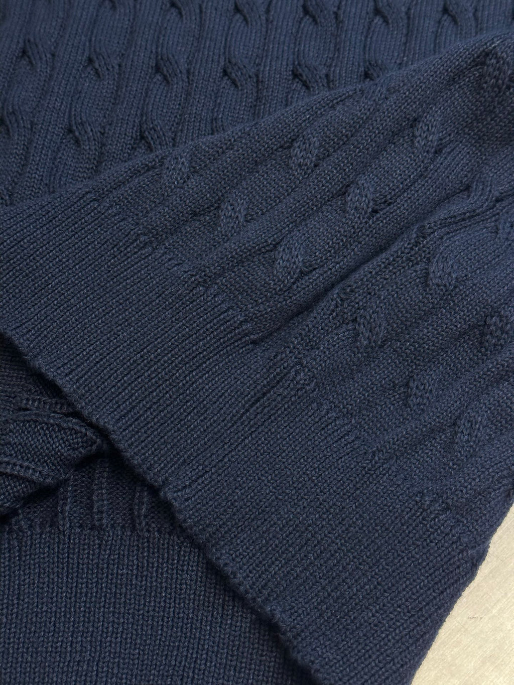 Navy cable-knit polo shirt sleeve and textured knit pattern