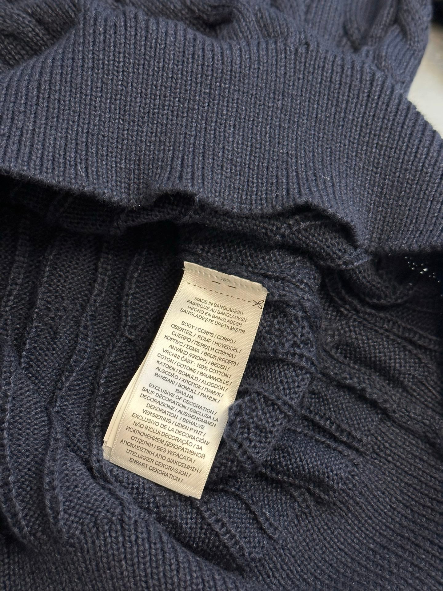 Navy polo shirt with stitched fabric label at the neck opening