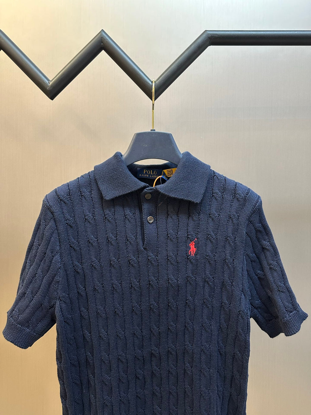Navy knit polo shirt with spread collar, buttons, and small red horse logo
