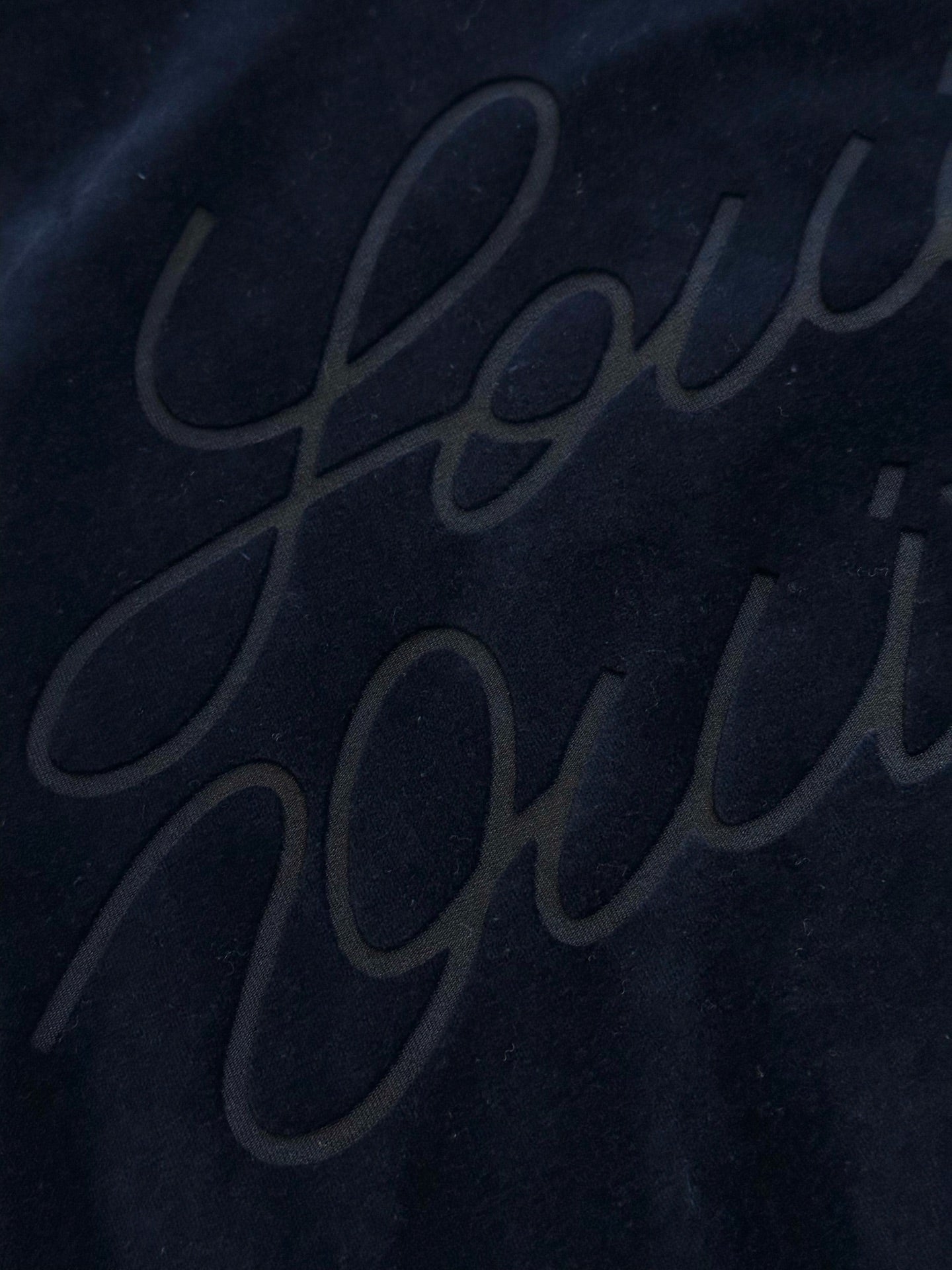 Navy jacket with subtle embossed script logo on back panel