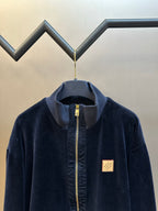 Navy zip-up jacket with stand collar, gold zipper, small logo patch on chest
