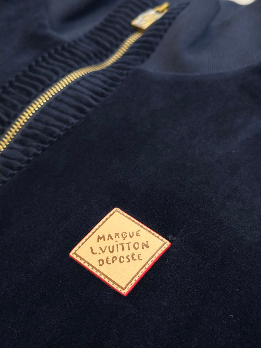 Navy jacket logo patch near zipper with gold-outlined label