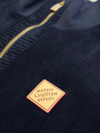 Navy jacket logo patch near zipper with gold-outlined label