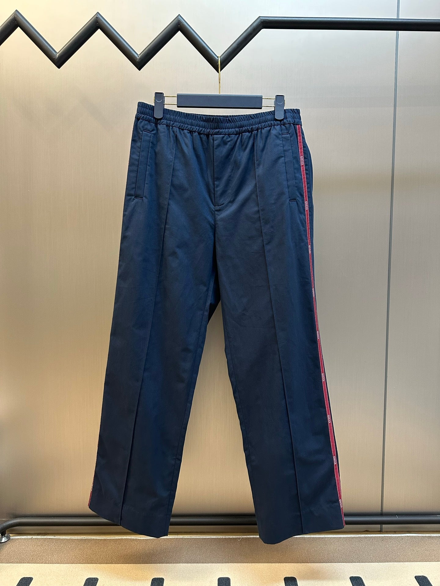 Gucci navy pants with elastic waistband and side red stripe on hanger