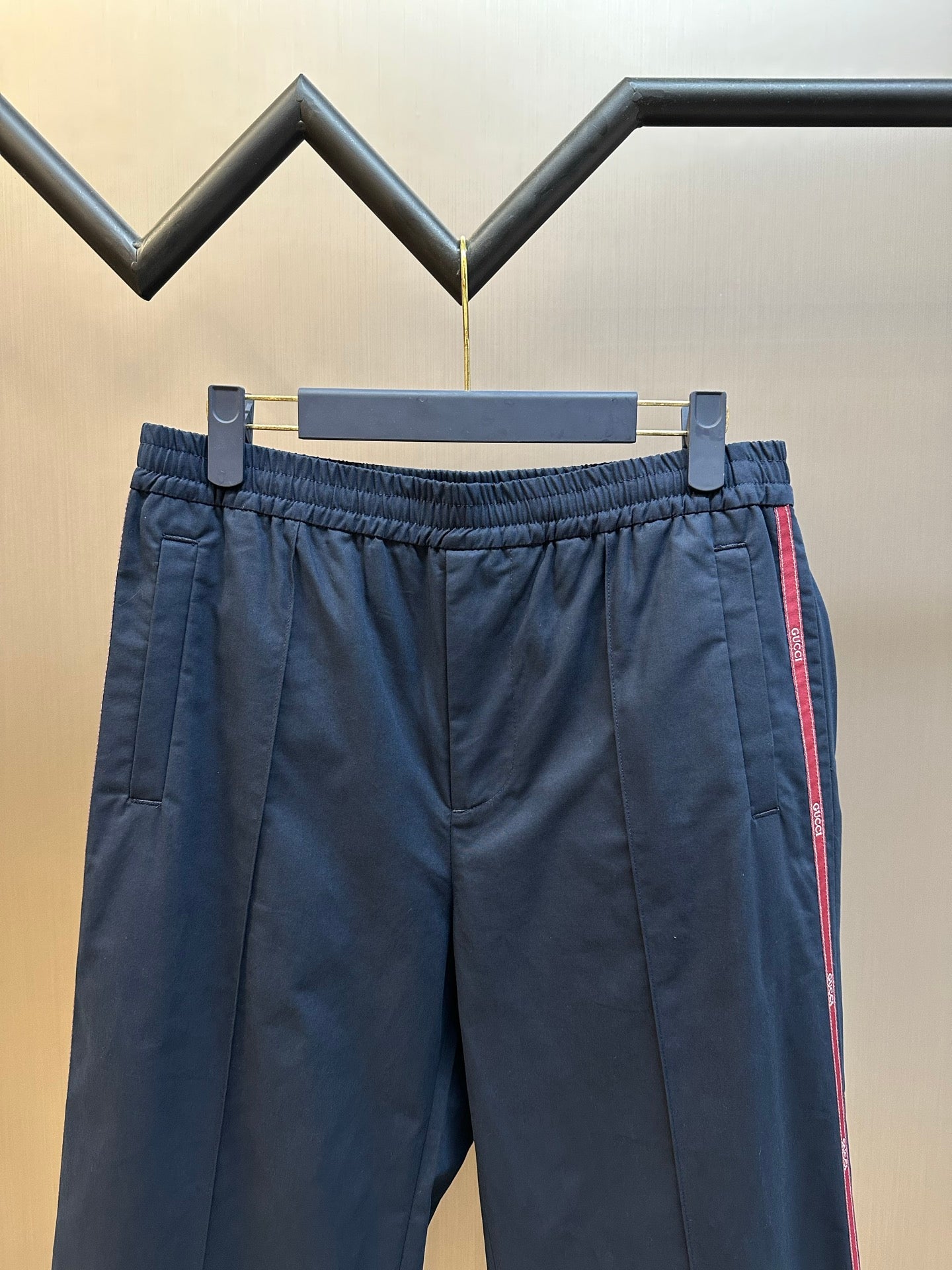 Navy pants with elastic waistband and side red stripe, front view on hanger