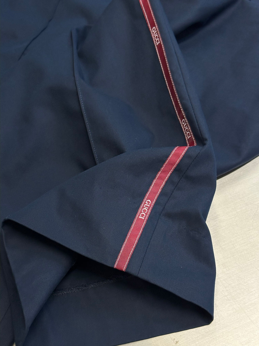 Navy pants close-up with red-trim side stripe and stitched seam