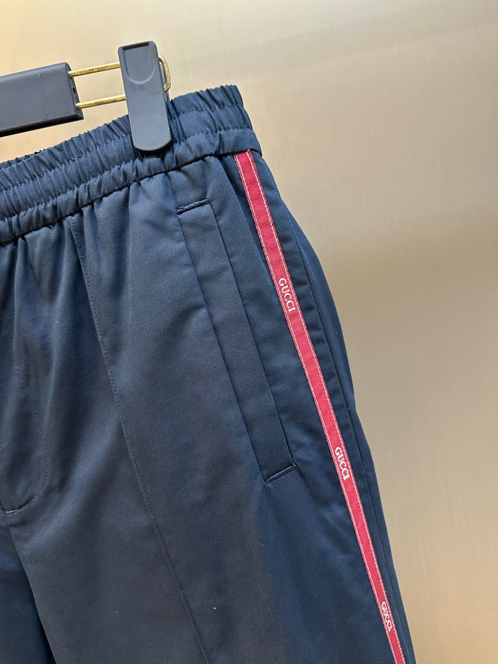 Close-up of navy pants with elastic waistband and red side stripe