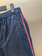 Close-up of navy pants with elastic waistband and red side stripe