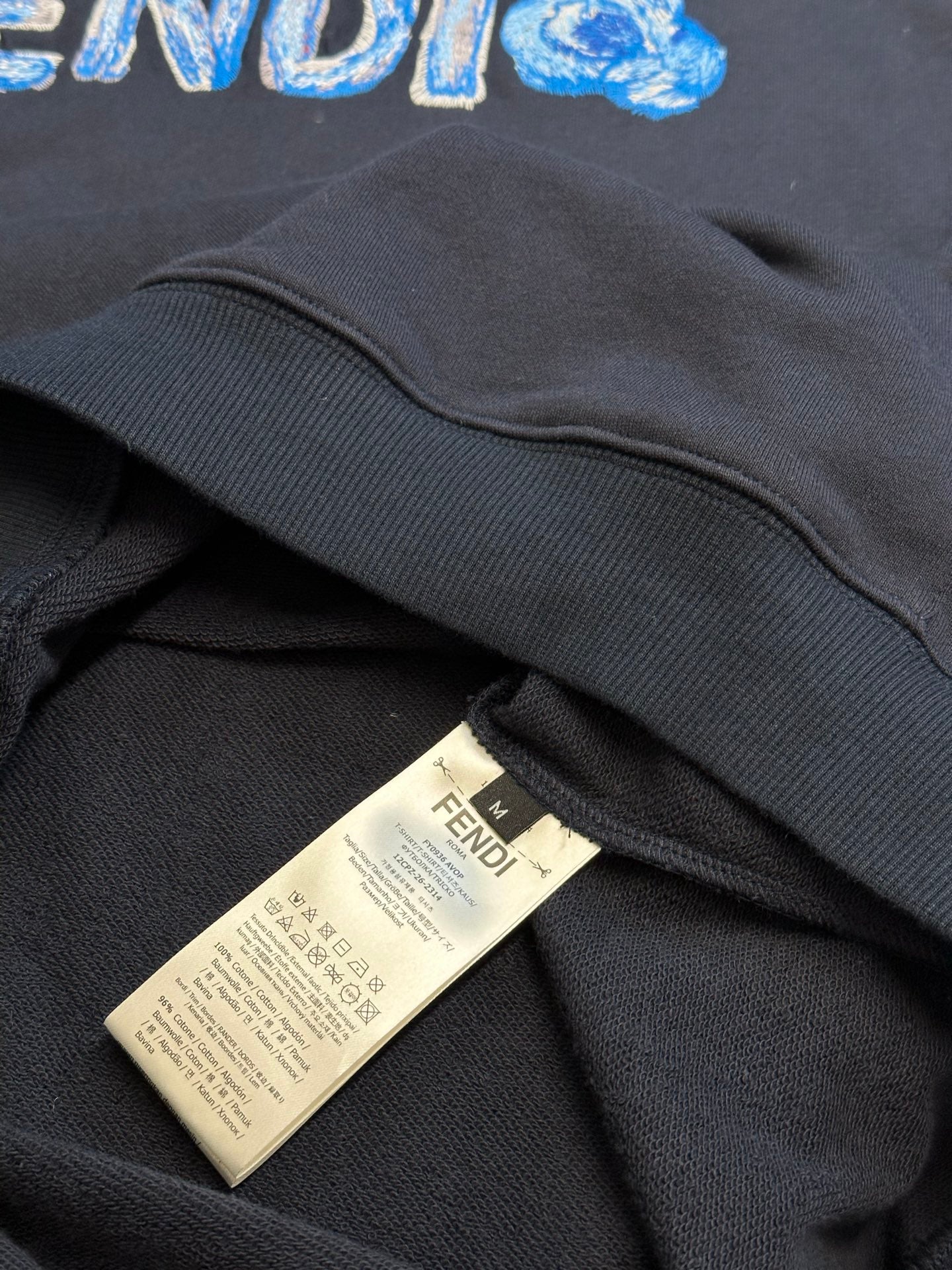 Navy hoodie with white care label near ribbed hem