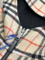 Burberry plaid fleece fabric closeup, cream with black and red grid, blue drawcord and zip